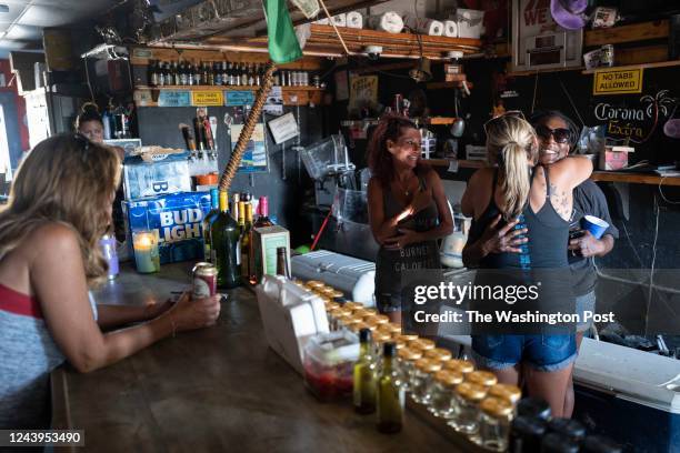 SAN CARLOS ISLAND FL - OCTOBER 7, 2022 Tina Tomasino, center, says goodbye to a
friend in her bar that also gives away free food on October 7, 2022 in San
Carlos Island, Florida. Tomasino, the owner of Hurricane Tinas 5 Star Dive Bar,
has been feeding people, many who lost everything in Ians storm surge, and
giving away beer. She said that the donations have been incredible and have been
helping people in her community cope with the losses. Hurricane Ians storm surge
caused catastrophic damage and an unknown number of deaths on the barrier...